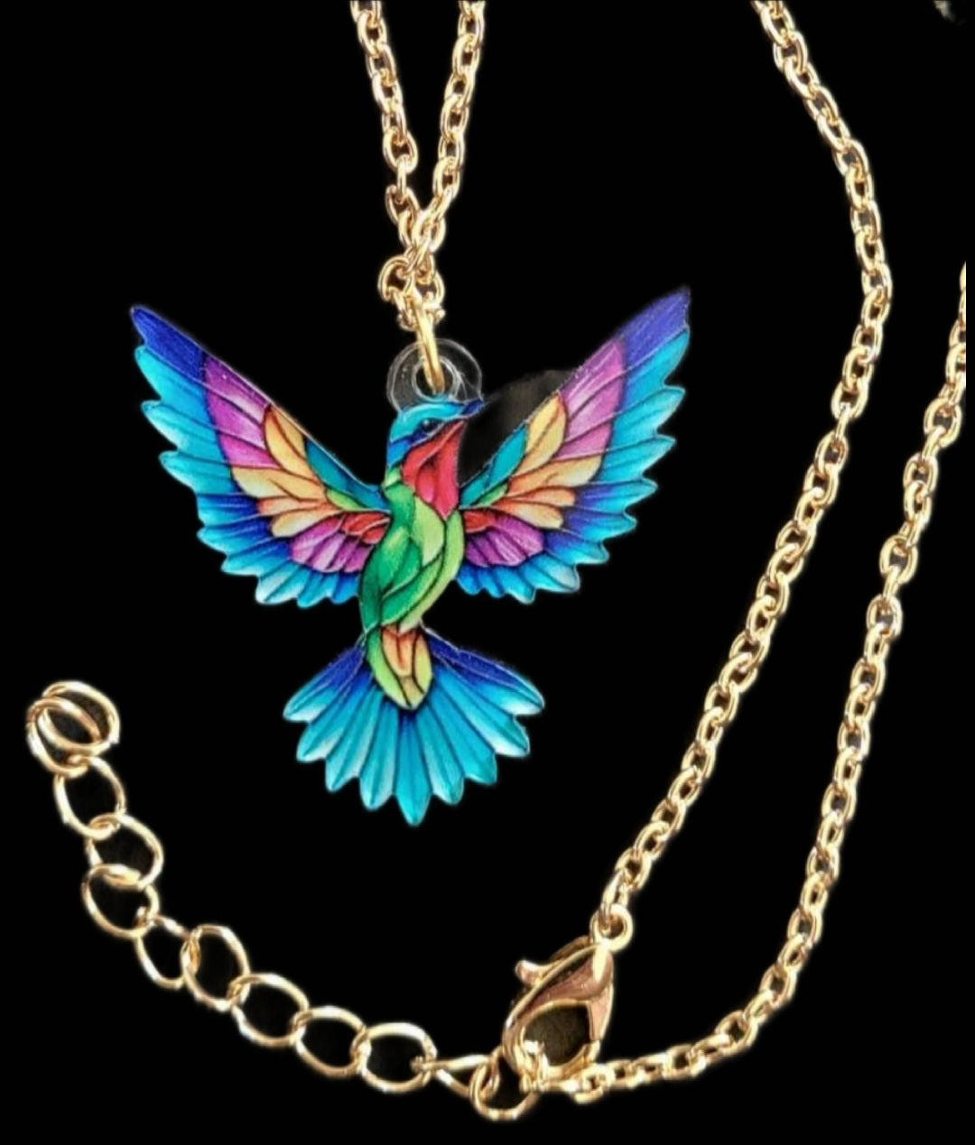 Kolibri Kette türkis lila mit goldfarbenem Anhänger auf schwarzem Hintergrund