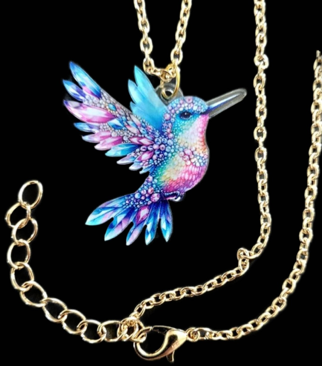 Kolibri Kette blau rosa mit goldfarbener Kette auf schwarzem Hintergrund
