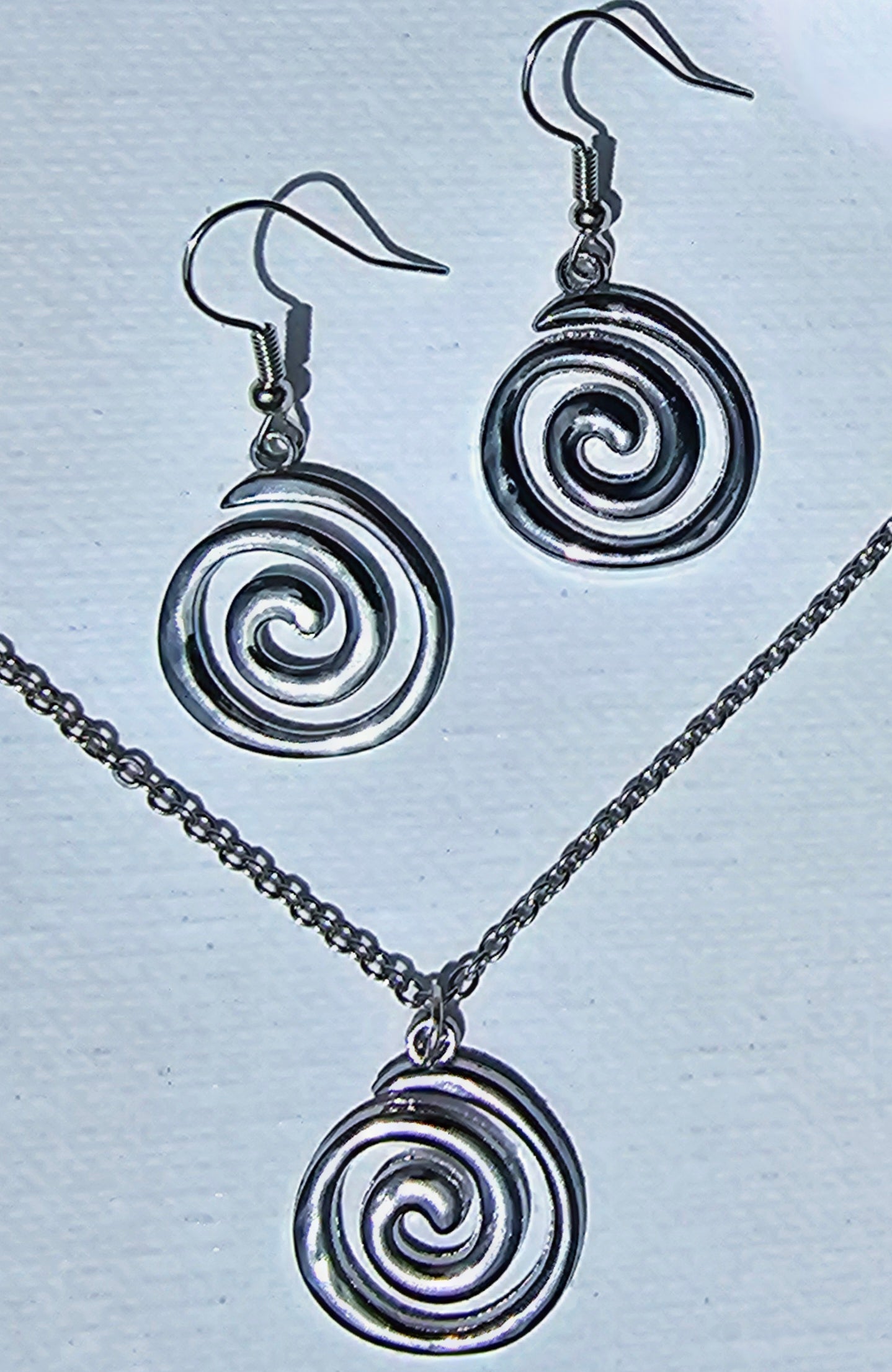Schmuckset Spirale Edelstahl Kette und Ohrringe auf hellem Hintergrund